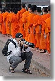 asia, asian, cameras, colors, laos, luang prabang, men, monks, oranges, people, photographing, procession, vertical, photograph