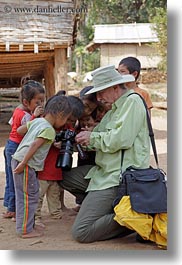 asia, asian, cameras, childrens, clothes, emotions, groups, hats, laos, men, people, river village, showing, smiles, tourists, vertical, villages, photograph