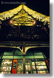 buildings, eiffel tower, europe, france, gifts, glow, glowing, lights, paris, perspective, shops, structures, towers, upview, vertical, photograph