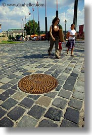 budapest, cobblestones, covers, europe, hungary, irons, manhole covers, manholes, materials, pedestrians, people, vertical, womens, photograph