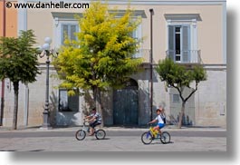 bikes, boys, buildings, europe, green, horizontal, italy, people, puglia, trani, trees, white, photograph