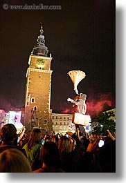 bell towers, buildings, clock tower, cones, crowds, europe, krakow, men, nite, people, performance, poland, structures, vertical, photograph