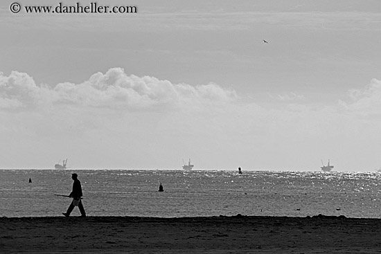 man-walking-on-beach-w-oil-rigs-bw.jpg