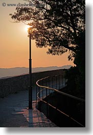 behind, cobblestones, croatia, dusk, europe, glow, lamp posts, lights, materials, motovun, nature, scenics, silhouettes, sky, stones, sun, sunsets, trees, vertical, photograph