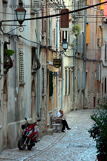 man-sitting-by-motorcycle-on-narrow-street-2.jpg