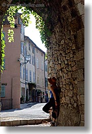 arches, archways, clothes, cobblestones, covered, europe, france, hats, ivy, looking, materials, nature, people, plants, provence, seillans, stones, structures, vertical, womens, photograph