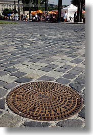 budapest, cobblestones, covers, europe, hungary, irons, manhole covers, manholes, materials, vertical, photograph