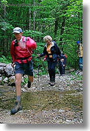 crossing, europe, forests, groups, hikers, hiking, lush, men, slovenia, stream, vertical, womens, photograph